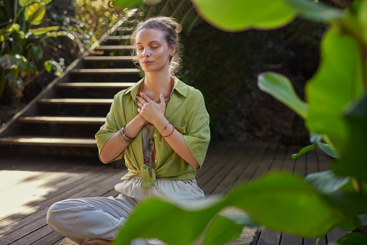 Peaceful woman sits cross-legged in a meditative state, hands over her heart