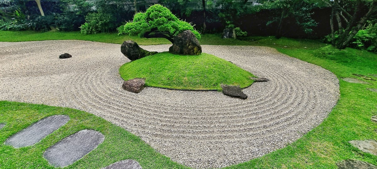 Serene and meticulously composed traditional Japanese rock garden, also known as a Zen garden (Karesansui), characterized by its raked gravel patterns and strategically placed elements
