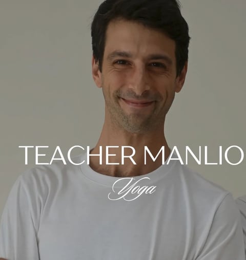 Portrait of Teacher Manlio, a yoga instructor, wearing a white t-shirt against a neutral background
